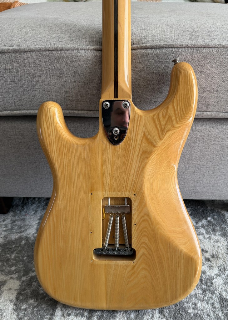 Back view of a wooden electric guitar showing its smooth finish and bridge assembly.